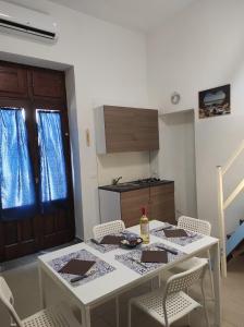una cucina con tavolo e sedie bianchi, un tavolo e una porta di Aeolian Sea House a Santa Marina Salina