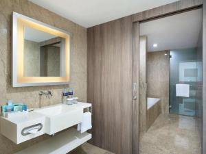 a bathroom with a sink and a mirror at Novotel Jakarta Gajah Mada in Jakarta