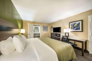 ein Hotelzimmer mit einem großen Bett und einem Schreibtisch in der Unterkunft Quality Inn & Suites - Garland in Garland