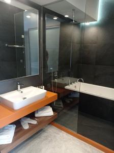 ein Badezimmer mit einem Waschbecken, einer Badewanne und einem Spiegel in der Unterkunft Petra Hotel in Agia Galini