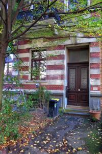 ein Backsteinhaus mit einer Holztür und einem Baum in der Unterkunft Gästeappartement im Atelierhaus in Wuppertal