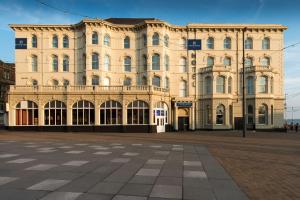 a large tan building with a square in front of it at Forshaws Hotel - Blackpool in Blackpool