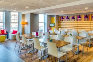 uma sala de jantar com mesas e cadeiras brancas em Forshaws Hotel - Blackpool em Blackpool