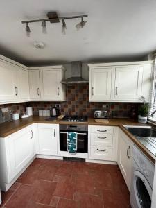 a kitchen with white cabinets and a stove top oven at Feather and Twigs Cottage, Croston in Croston
