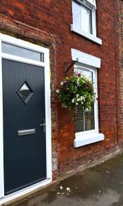 a brick house with a black door and a window at Feather and Twigs Cottage, Croston in Croston +4 photos