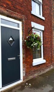 a brick house with a black door and a window at Feather and Twigs Cottage, Croston in Croston