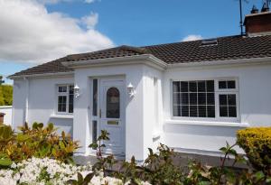 una casa blanca con una puerta blanca y algunos arbustos en Rose Haven private home between Dungannon & Omagh en Dungannon