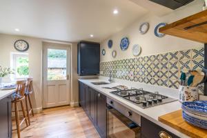 a kitchen with blue and white tiles on the wall at Vine Cottage, Charlbury in Charlbury