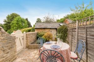 a patio with a table and chairs and a fence at Vine Cottage in Charlbury
