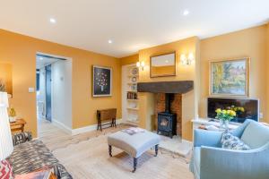 a living room with yellow walls and a fireplace at Vine Cottage in Charlbury
