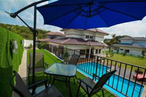 a patio with chairs and a blue umbrella and a pool at Homestay PD Villa 969 with Private Pool in Port Dickson