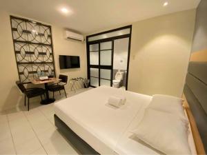 a bedroom with a white bed and a table and a desk at The Hub District Garden Suites in Manila