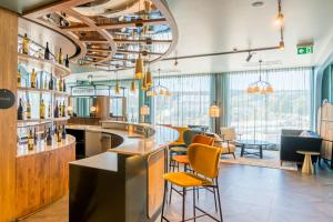 a bar at a restaurant with orange chairs and tables at Hotel D Bulle - La Gruyère in Bulle