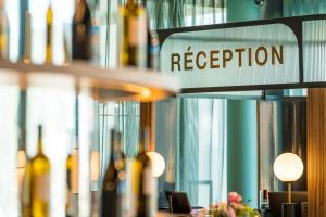 a reception sign in a room with bottles of wine at Hotel D Bulle - La Gruyère in Bulle
