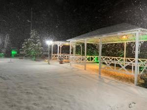 un cenador en la nieve por la noche en Hotel Taverna Zisi, en Ersekë