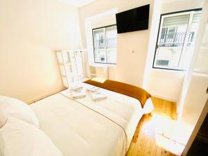 two beds in a small room with two windows at Glória 10 in Lisbon