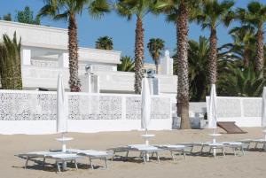 un gruppo di tavoli sulla spiaggia con palme di Hotel Florence a San Benedetto del Tronto