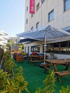 un groupe de tables de pique-nique et un parasol devant un bâtiment dans l'établissement Hotel ibis Leiria Fatima, à Leiria