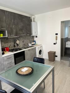 una cucina con tavolo in vetro e piano cottura di Apartment Verdi BARDOLINO a Bardolino