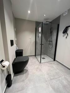 a bathroom with a black toilet and a shower at Notodden Sentrum Apartment NO 9 in Notodden