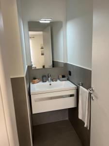 bagno con lavandino bianco e specchio di Apartment Verdi BARDOLINO a Bardolino