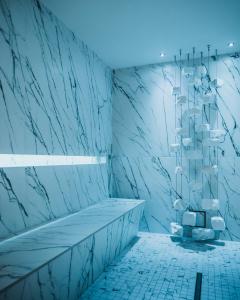 uma casa de banho com paredes em mármore e um lustre em Klein Fein Hotel Anderlahn em Parcines