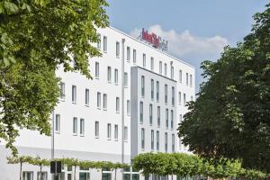 ein weißes Gebäude mit Bäumen davor in der Unterkunft IntercityHotel Ingolstadt in Ingolstadt