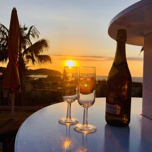 dos copas de vino y una botella en una mesa con la puesta de sol en B&B Villa Anna Wunderbar en Isquia