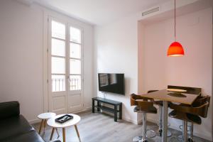 a living room with a couch and a table and a tv at Decô Apartments Barcelona-Sants in Barcelona