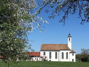 a white church with a tower on top of a field at Aich21 in Peißenberg