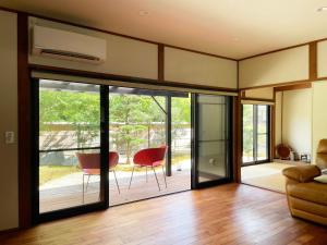a living room with sliding glass doors and red chairs at Akizuki Niwa (Garden) House in Asakura