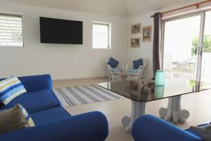 a living room with a blue couch and a glass table at Zenbreak Freshwater Beachfront 6 in Saint Michael
