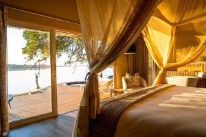 a bedroom with a bed and a view of the water at Victoria Falls River Lodge in Victoria Falls