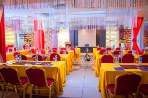 a banquet hall with yellow tables and red chairs at Golden Tulip Garden City Hotel - Rivotel in Port Harcourt