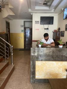 a man sitting at a counter in a lobby at Hotel Blue Palace By WB Inn in New Delhi