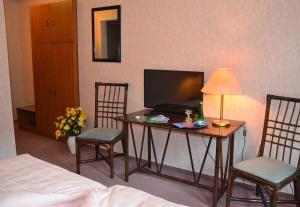a room with a table with two chairs and a television at Hotel Zur Hallenburg in Kurort Steinbach-Hallenberg