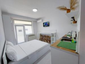 a white bedroom with a bed and a sink at Casuta cu Tei in Oradea
