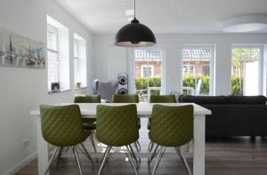 una sala da pranzo con tavolo bianco e sedie verdi di Haus Veronika links a Wyk auf Föhr