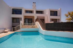 a house with a swimming pool in front of a building at Serenity Villa in Kórinthos