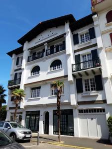 a white building with palm trees in front of it at Résidence Albina centre Hendaye Plage in Hendaye