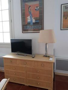 a television on top of a wooden dresser with a lamp at Résidence Albina centre Hendaye Plage in Hendaye