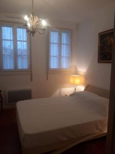a bedroom with a white bed with a lamp and windows at Résidence Albina centre Hendaye Plage in Hendaye