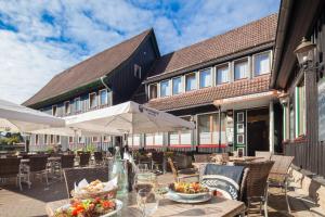 un restaurante al aire libre con mesas, sillas y sombrillas en Altes Forsthaus Braunlage, en Braunlage