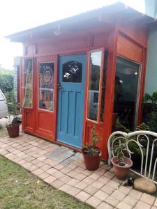 una pequeña casa con una puerta azul y roja en BohippienJBAY, en Jeffreys Bay