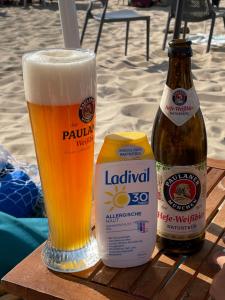 a glass of beer sitting next to a bottle of beer at Aloha-Olmenduin in Serooskerke