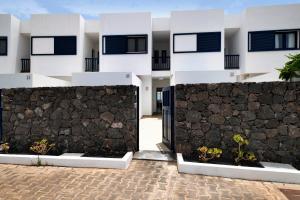 a house with a retaining wall and a stone fence at Ajaches 23 in Puerto Calero