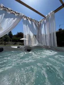 Una piscina de agua con cortinas blancas. en L'ESCALE Chambres et table d'hôtes, en Verdun-sur-le-Doubs