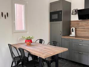 a kitchen with a wooden table with black chairs at Maisonnette indépendante avec jardin/patio in Nîmes
