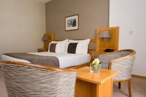 Una habitación de hotel con una cama, una mesa y sillas. en Hotel Rainha D. Amélia, Arts & Leisure, en Castelo Branco