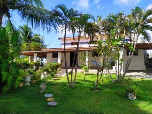 a house with palm trees in front of it at Casa de praia Tabatinga, sossego, sol e mar na Paraíba in Conde